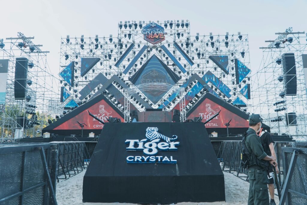 pexels-photo-13051278-13051278 Outdoor stage setup for a major event featuring Tiger Crystal branding and structural lighting.